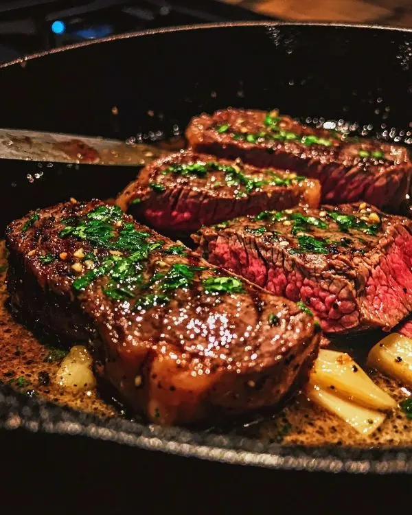 Faux-Filet, Bavette, Hampe: Mes 3 Morceaux de Bœuf 8 Bavette de bœuf cuite à la poêle avec beurre à l’ail, servie dans une poêle en fonte avec un couteau posé à côté.