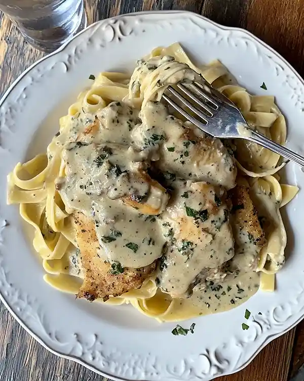 Assiette de poulet en sauce familiale servi avec des pâtes tagliatelles, repas fait maison